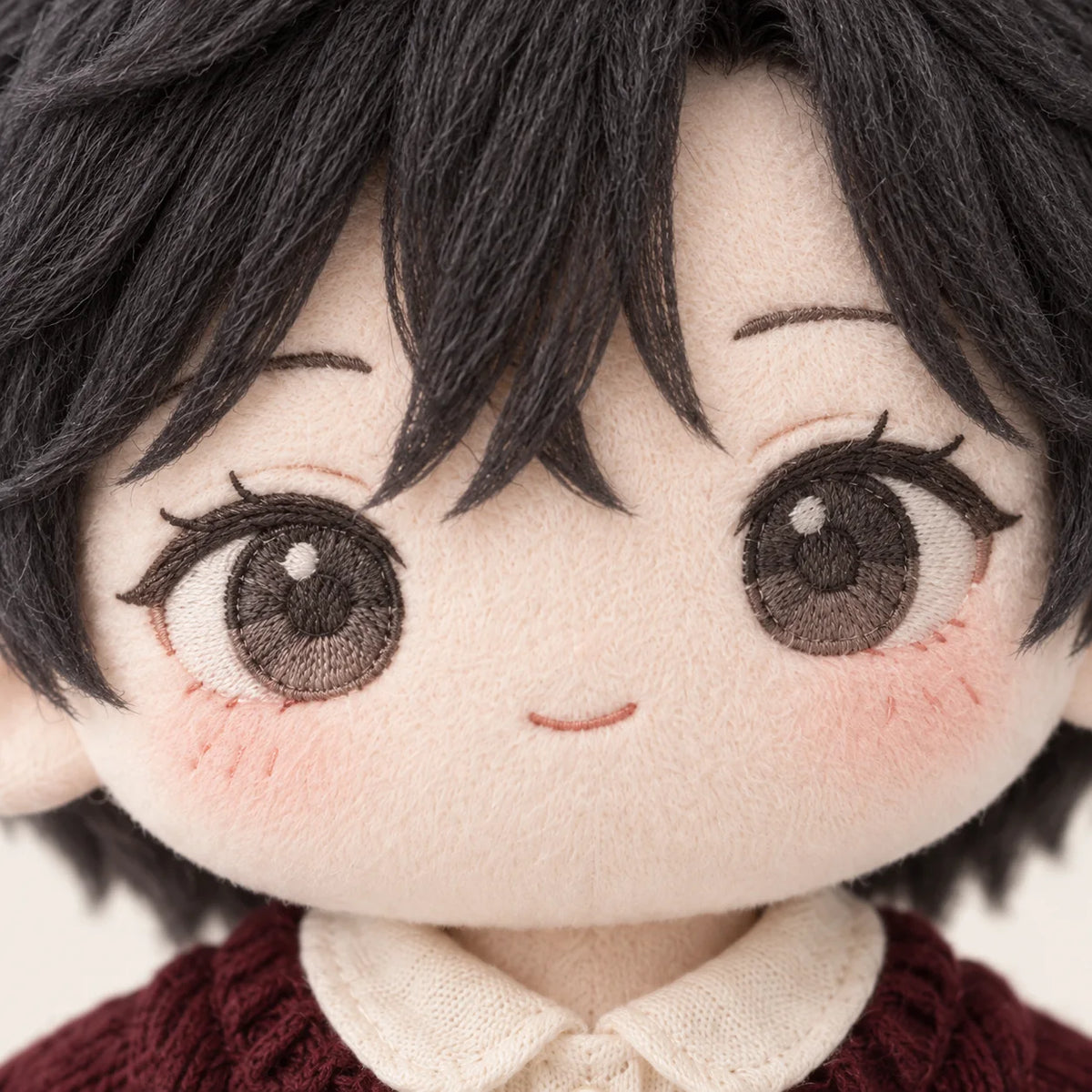 Close-up illustration of a cotton doll’s gray embroidered eyes and small smile.