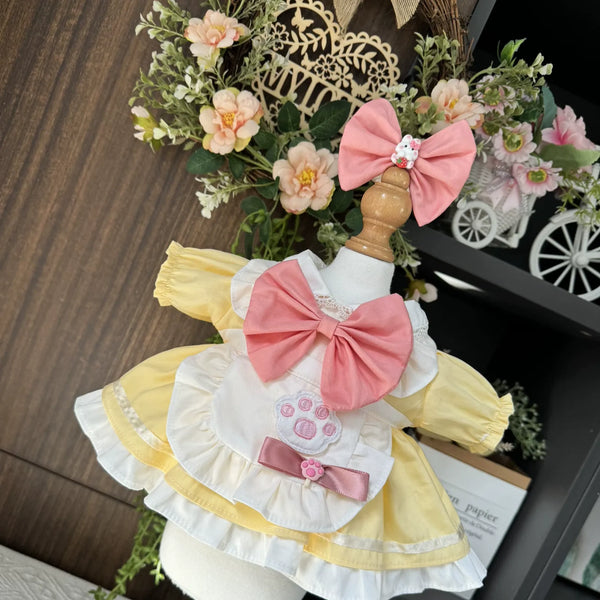 Lemon Paw Print Apron Dress & Hair Bow for cotton dolls: pale yellow dress, white apron, coral-pink bow, pink hair bow, front view