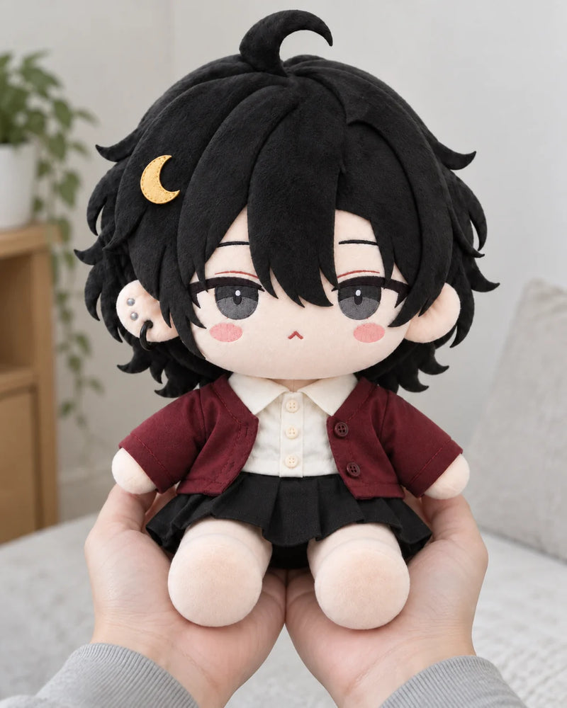 Hands holding a black-haired OC cotton doll with grey embroidered eyes, a gold crescent and burgundy cardigan.